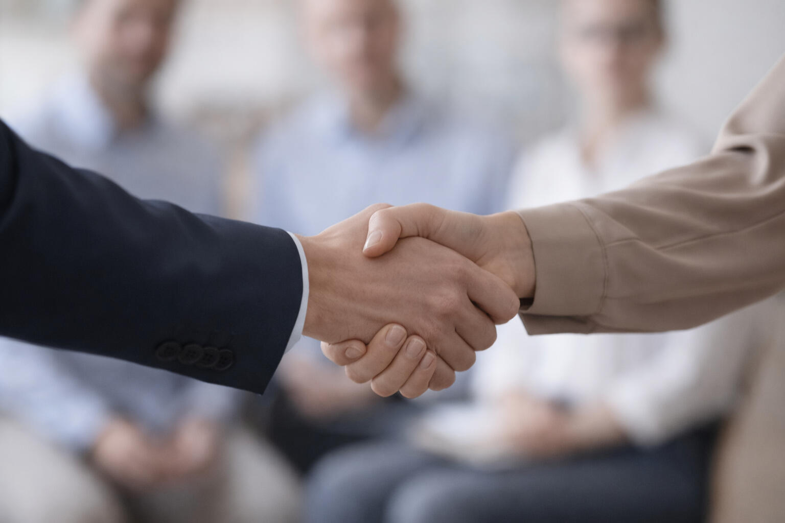 Leadership Series - Building Confident, Capable Leaders Business leaders shaking hands during a formal meeting with team members behind them